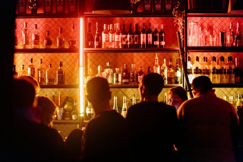 Bar by Aleskandr Popov bar lit up surrounded by people